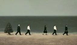 bankers walking on a beach by a Christmas tree