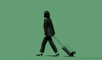 an Asian woman dragging a suitcase against a greenbackground